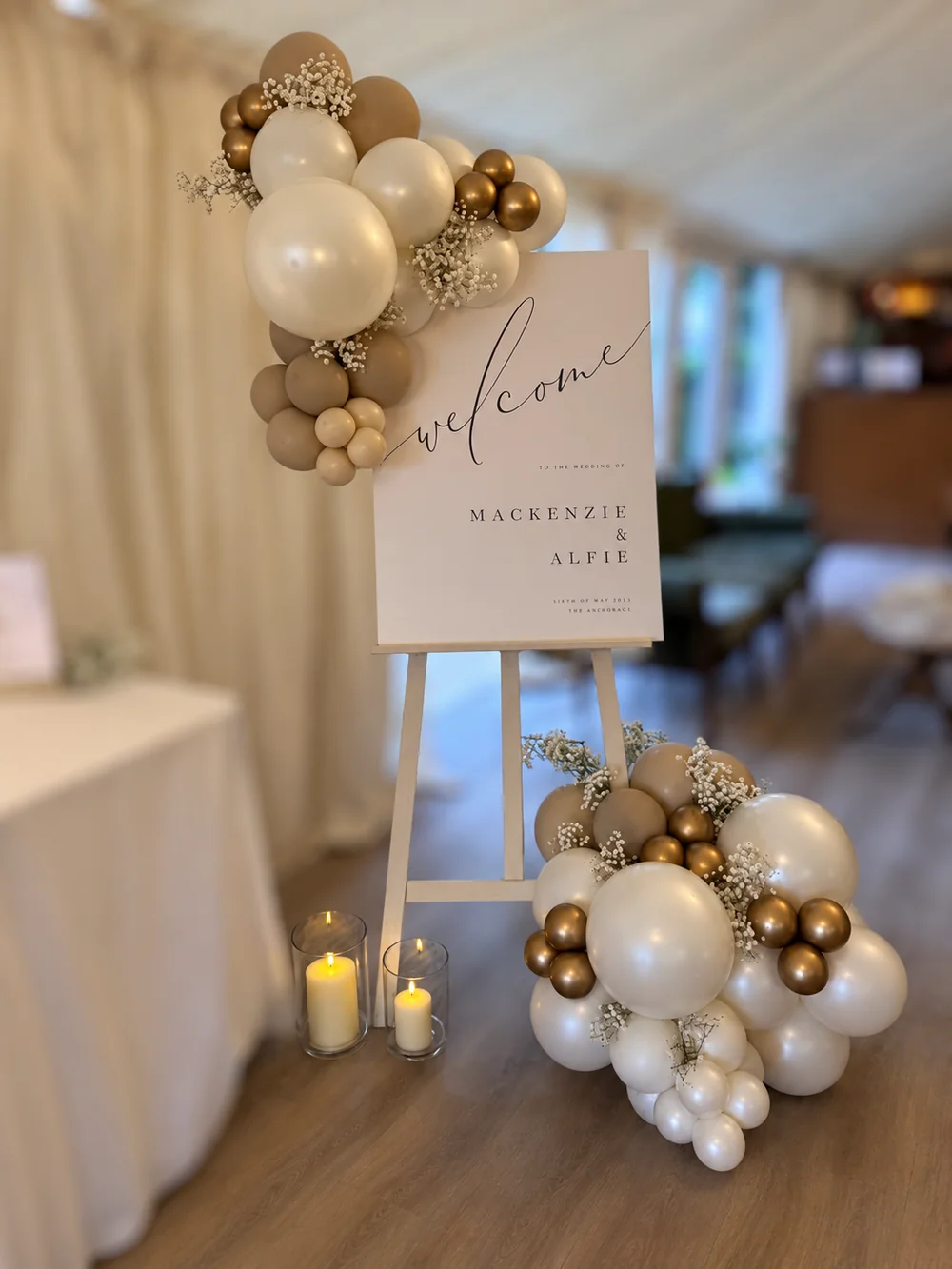 Full cream and champagne balloon installation with a welcome sign, candles and lower balloon arrangement
