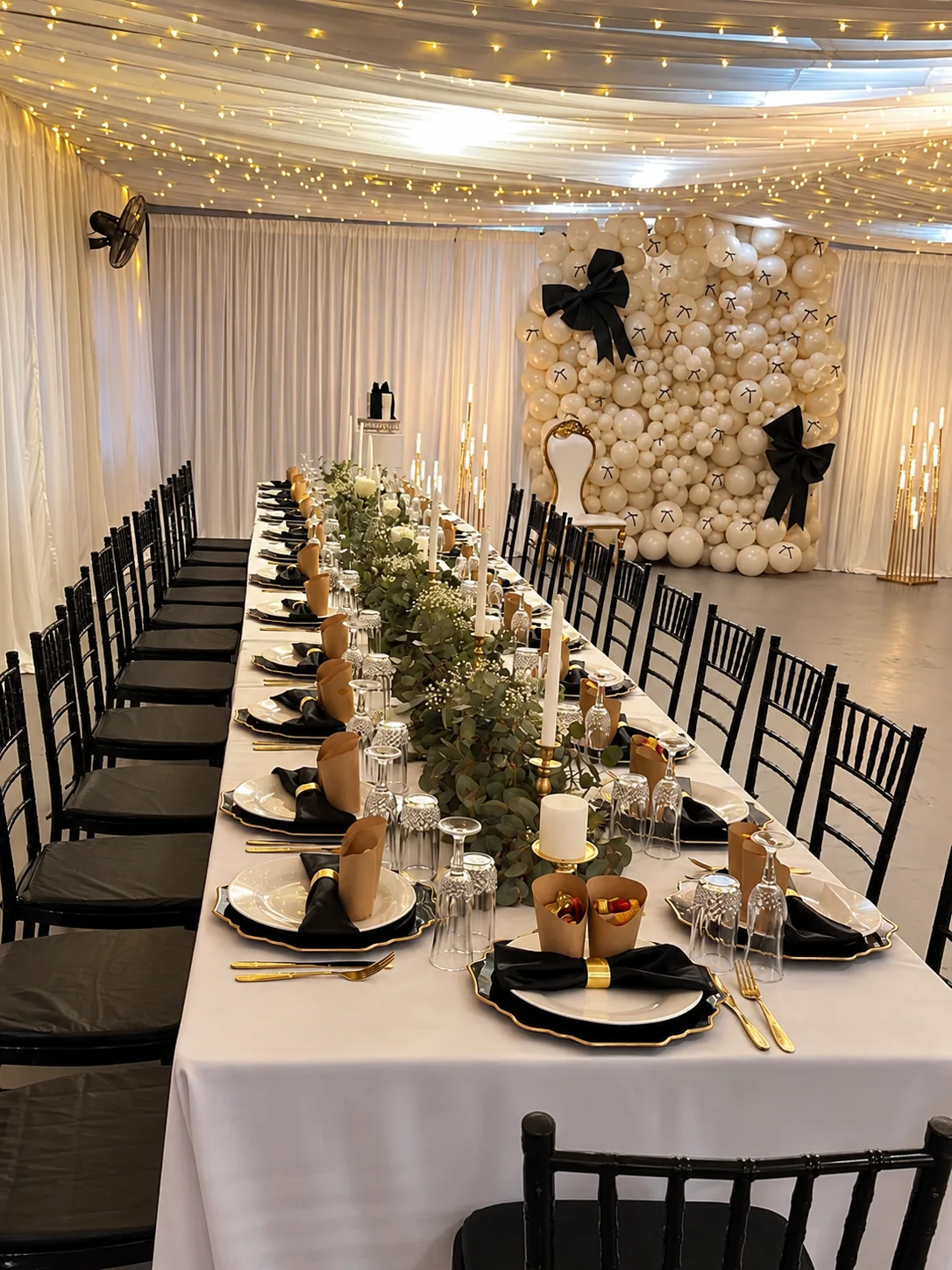Elegant black, ivory and gold tablescape with candlelight and balloon décor