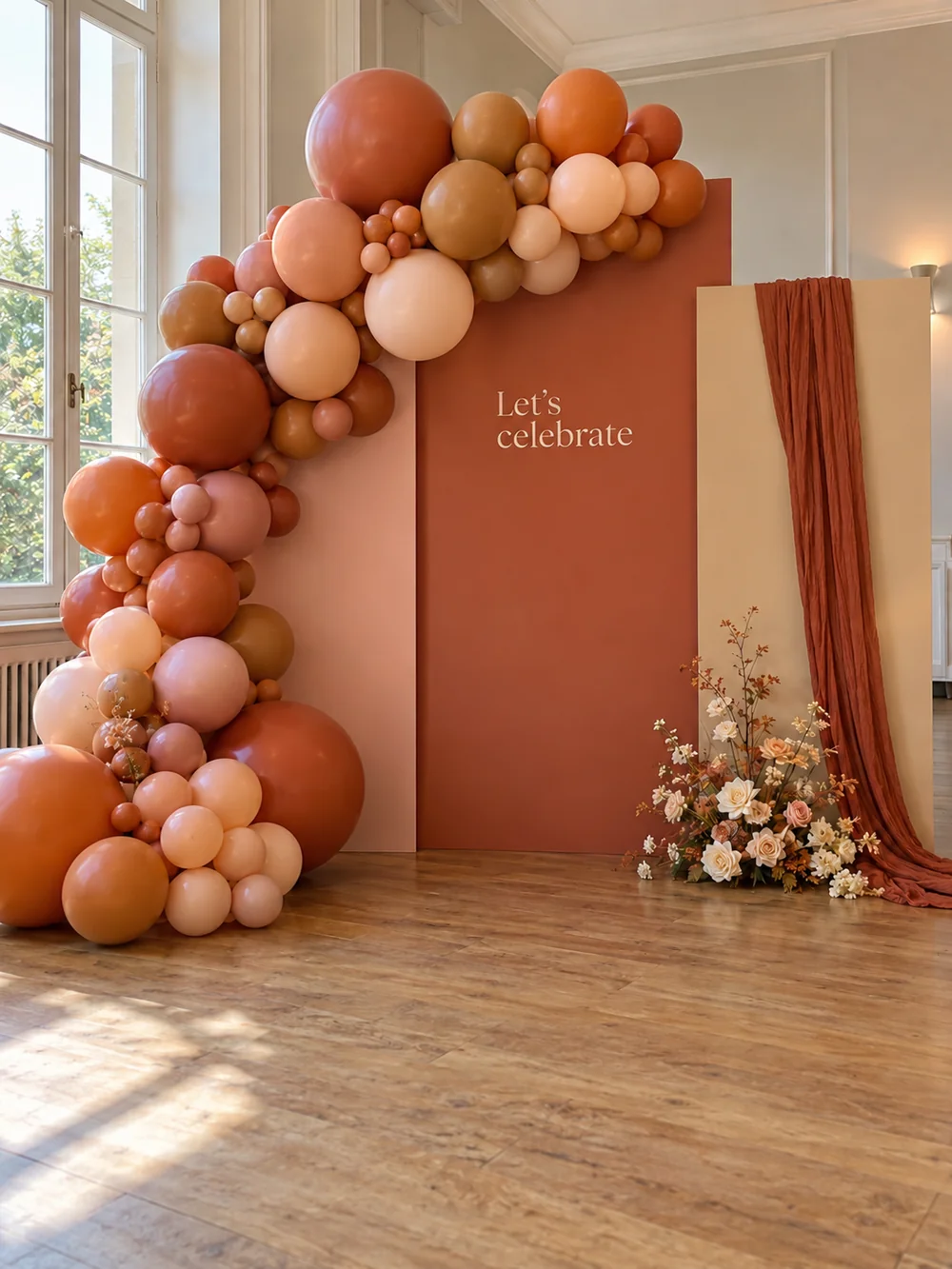 Terracotta, peach and blush balloons around a Let's celebrate backdrop with flowers